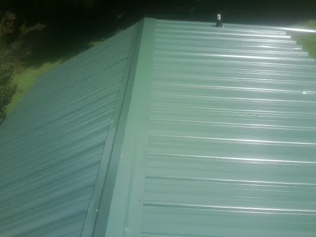 New green metal panels meeting at the ridge of a roof — Flat Roof Repair work by our crew in Miami